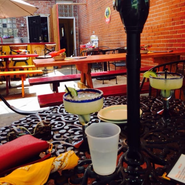 Two margaritas on a black wrought iron table at Uno Mas Taqueria y Cantina's outdoor patio.